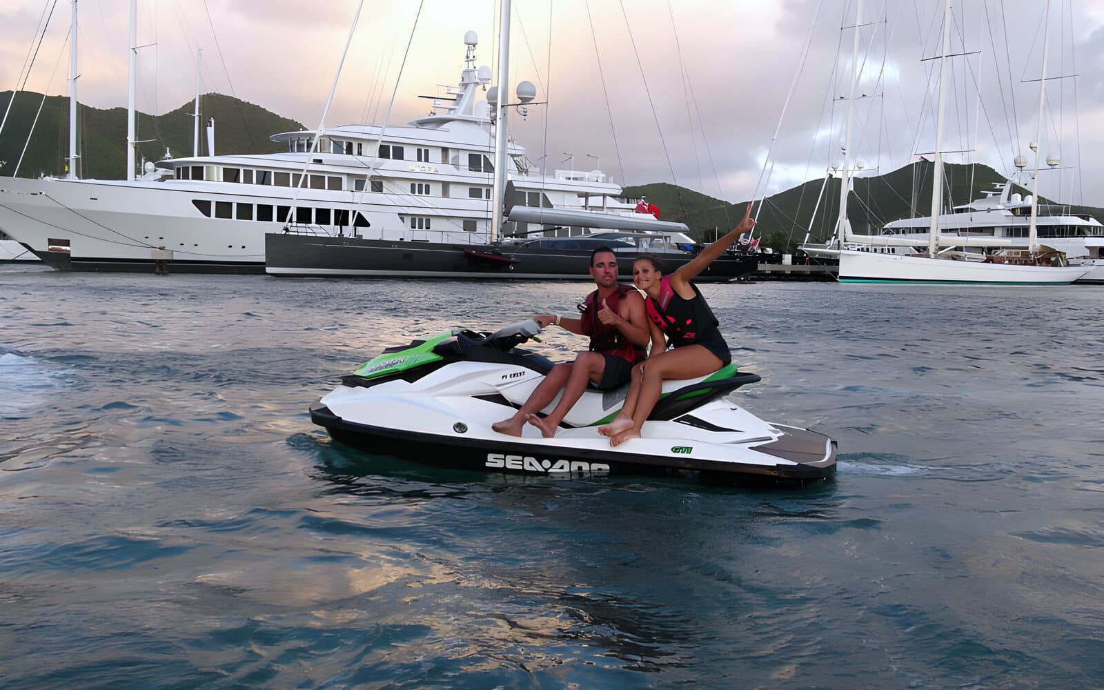 Two people on a jet ski in Simpson Bay Lagoon, in front of the yachts