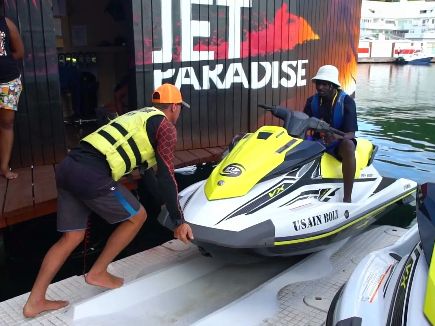 Un instructor empuja un jet ski a lo largo del muelle, frente a la tienda de Jet Paradise