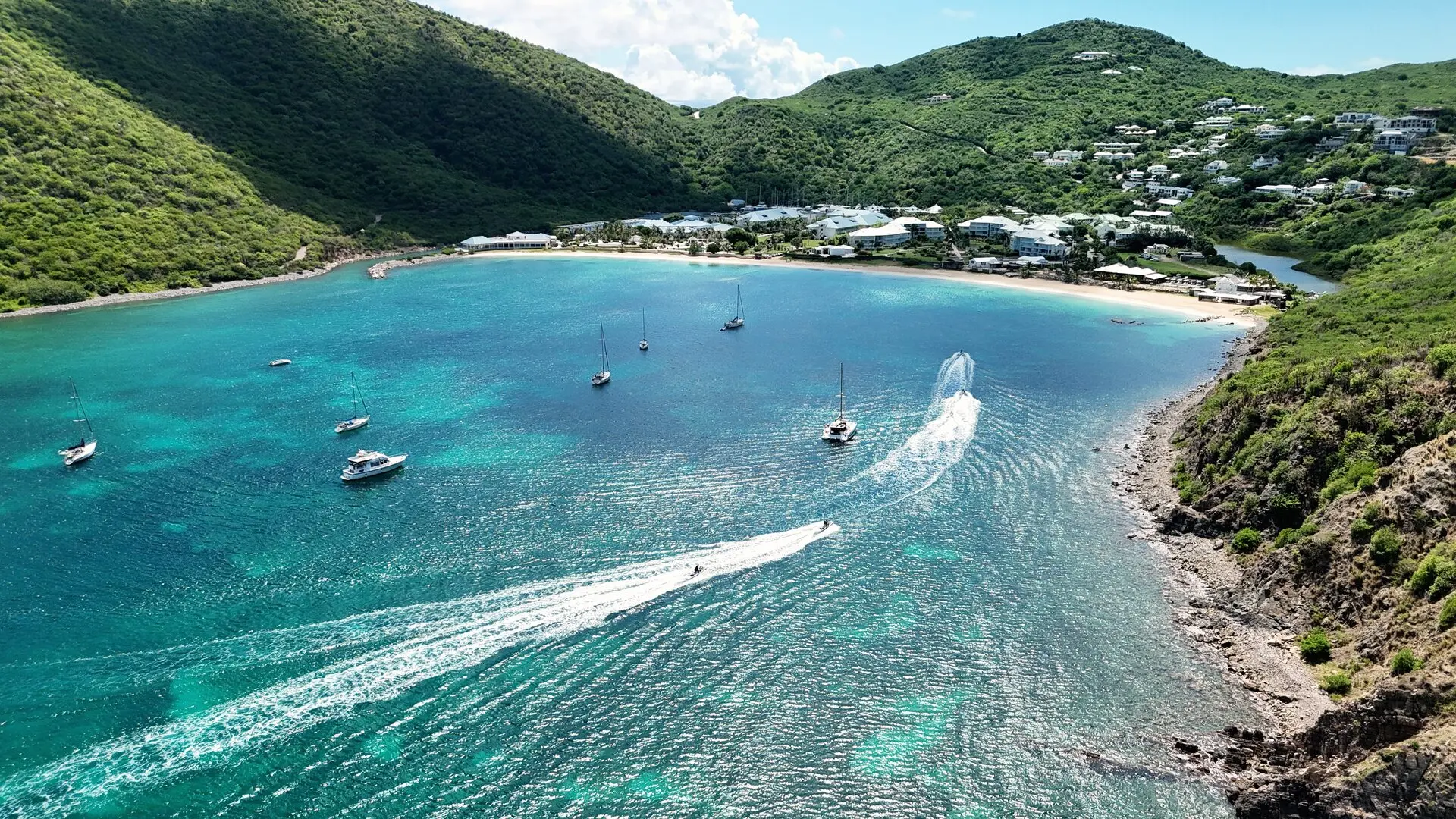 La bahía de Anse Marcel vista desde el cielo, dos jet skis y su estela sobre el agua turquesa