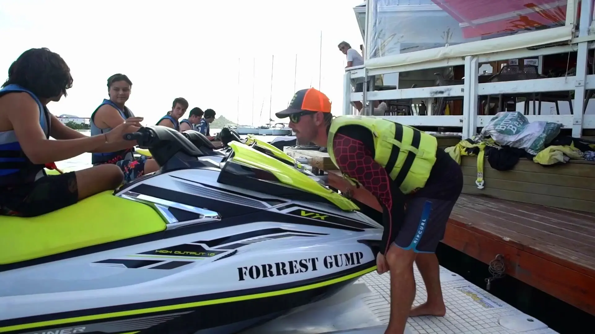 Un instructor ayuda a unos clientes a acomodarse en su jet ski, en el muelle