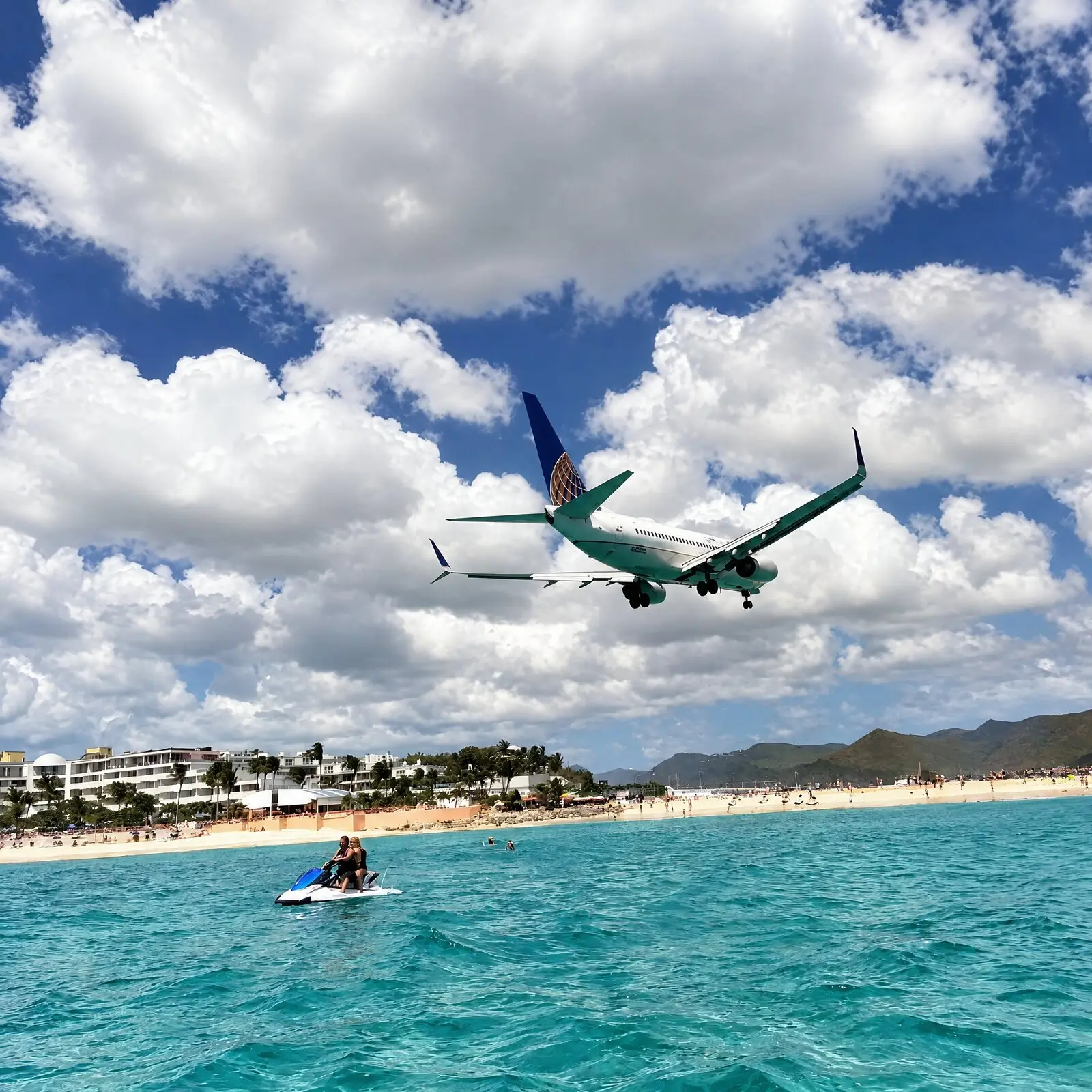 Un avión de pasajeros pasa rozando la playa de Maho, por encima de un jet ski en el agua turquesa