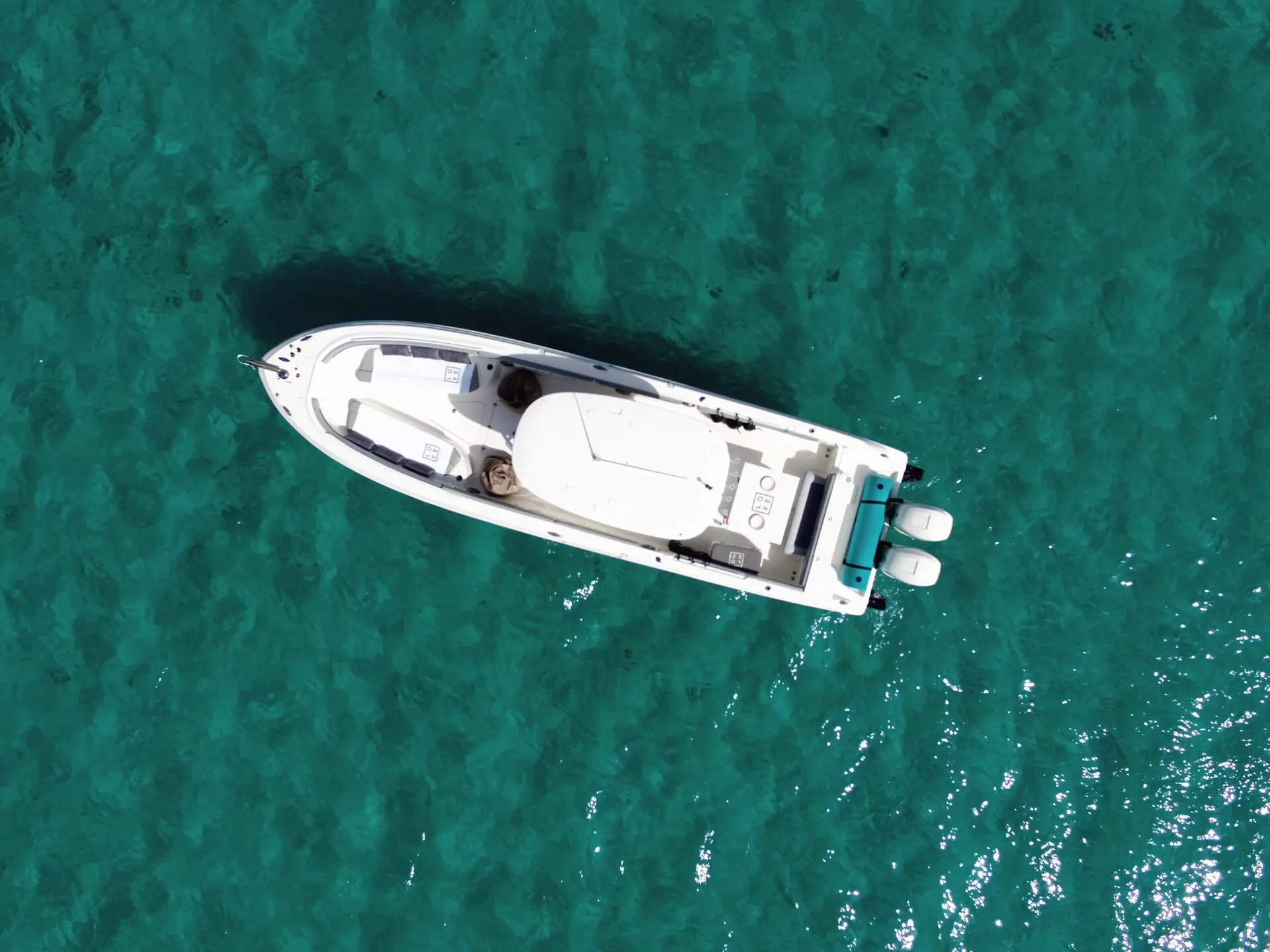 Un barco blanco visto desde arriba, detenido sobre el agua turquesa